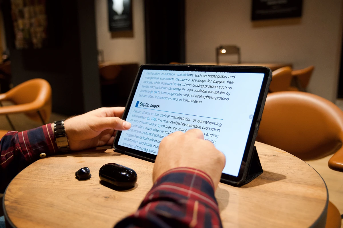 Znaczenie contentu w pozycjonowaniu: jak treść realnie pracuje na widoczność? Mężczyzna czyta artykuł na tablecie przy stoliku w kawiarni