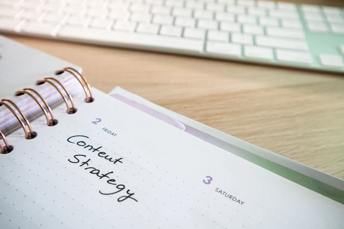 Ile kosztuje content marketing? Realne widełki i co wpływa na cenę Planer z odręcznym napisem Content strategy obok klawiatury na drewnianym biurku