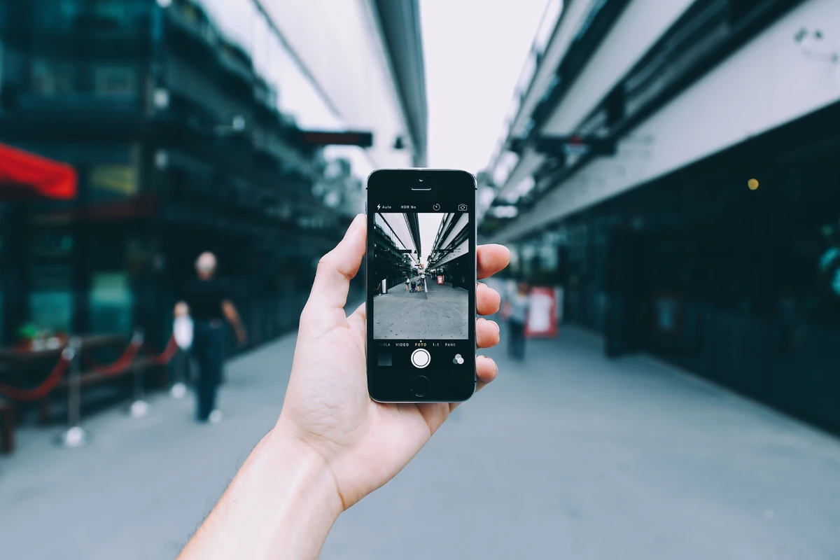 Optymalizacja treści pod wyszukiwanie głosowe: jak pisać naturalne odpowiedzi Dłoń trzyma smartfon, którym fotografuje ulicę w mieście