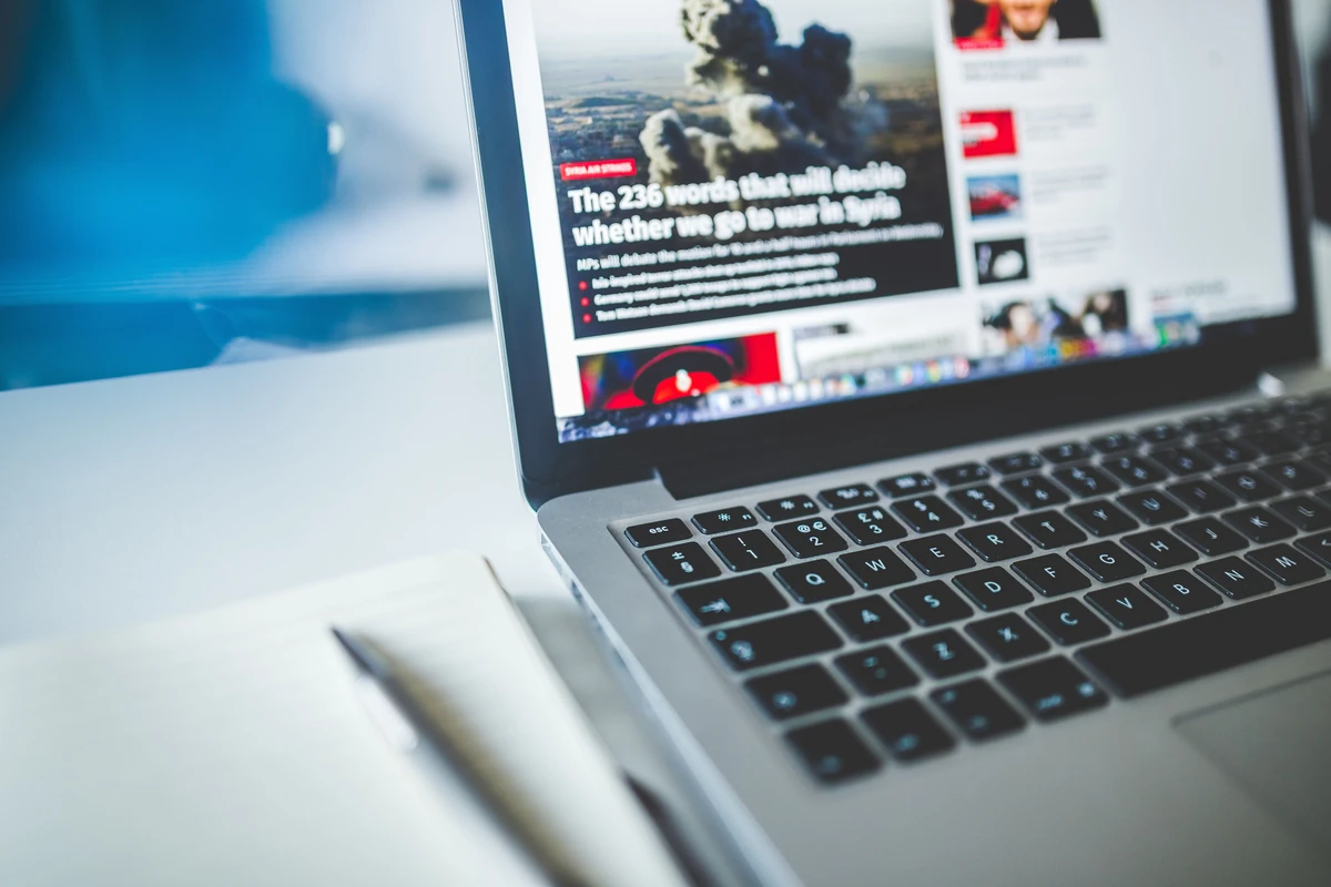 Pozycjonowanie strony one page: kiedy ma sens i jak zrobić to dobrze? Otwarty laptop z artykułem internetowym na ekranie i notes obok na biurku