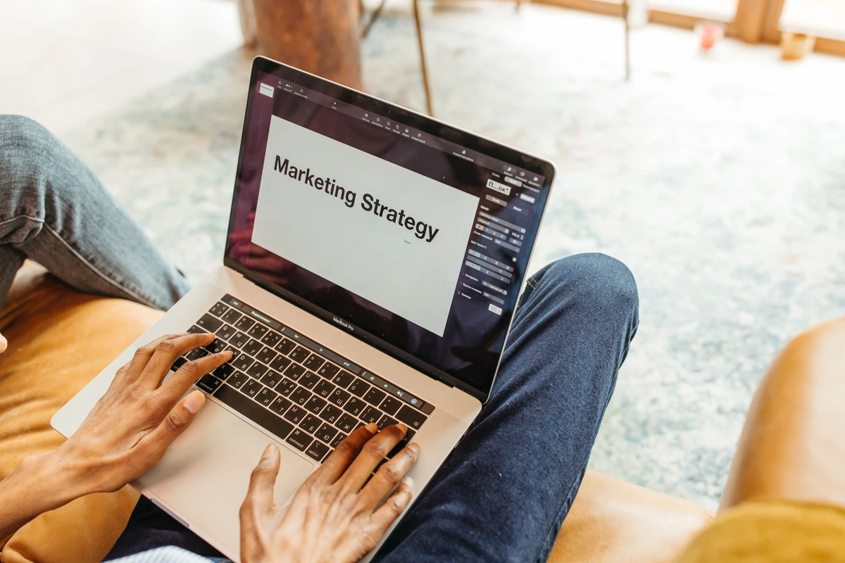 Google Ads dla firmy: jak zacząć reklamę bez przepalania budżetu Dłonie przy laptopie z prezentacją strategii marketingowej na ekranie