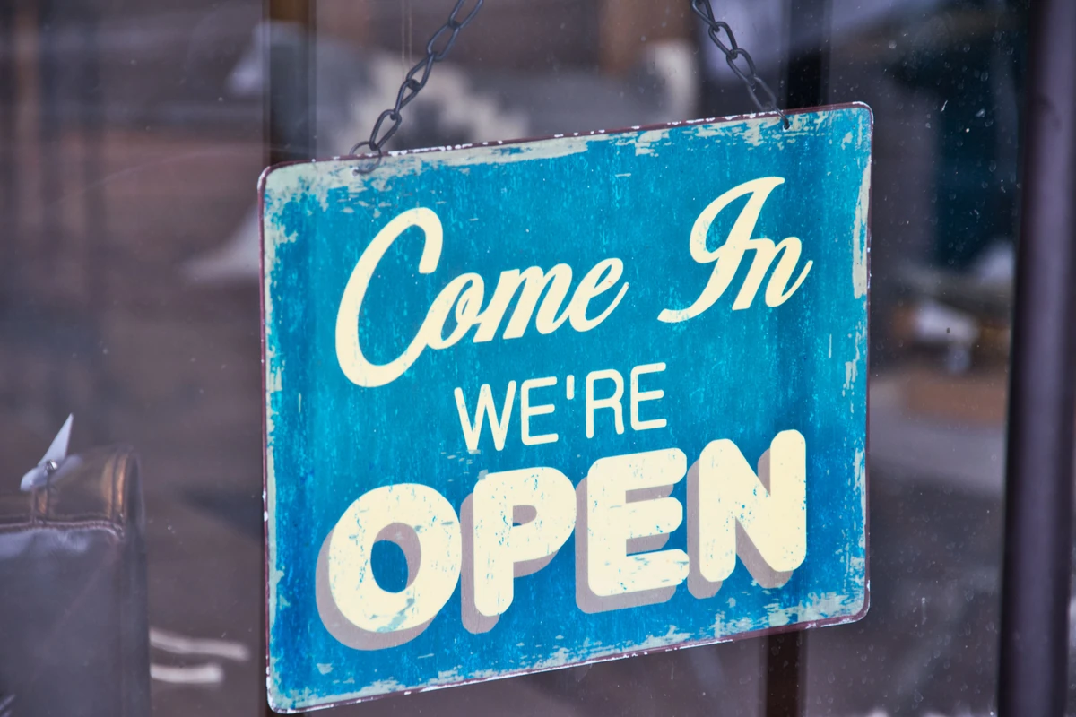 Niebieska tabliczka z napisem Come in, we're open na szklanych drzwiach sklepu
